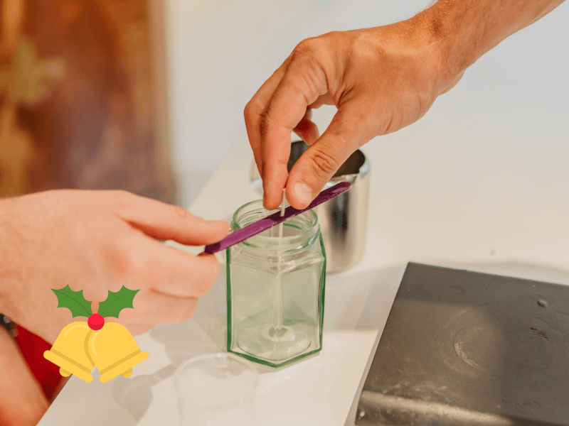 A reusable or recyclable glass jar containing a wick is ready to be filled with soy wax to make a DIY candle 